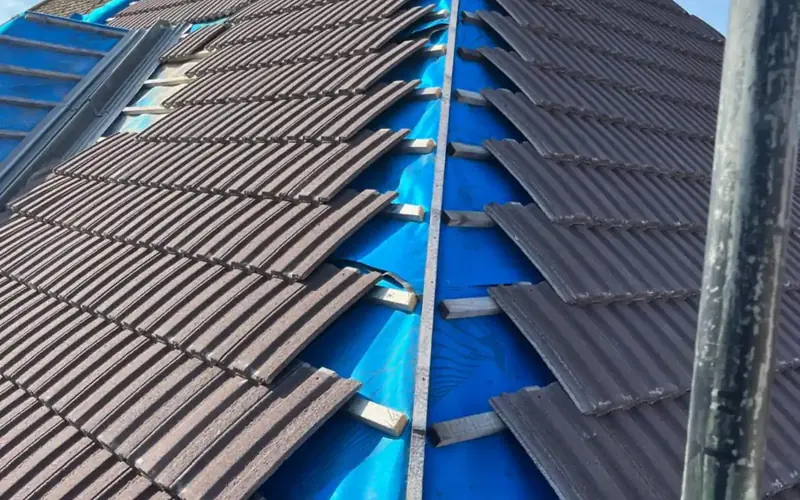 New interlocking tiles being laid over fresh battens on a re-roof, one of our jobs