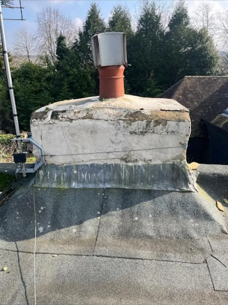 Rendered chimney stack with a cowled pot and lead at the base, rising from a felt flat roof