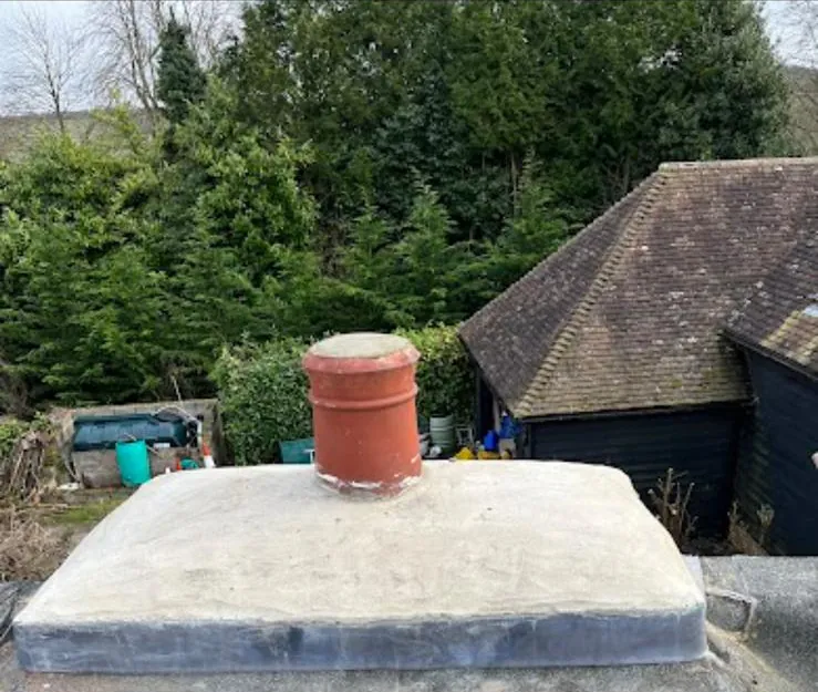 Chimney stack capped off with a clay pot, rising from a flat roof