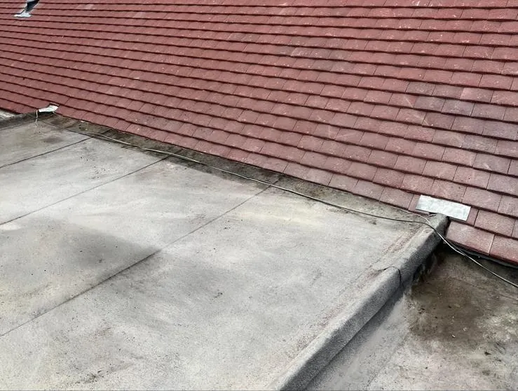 Red tile pitched roof meeting a felt flat roof