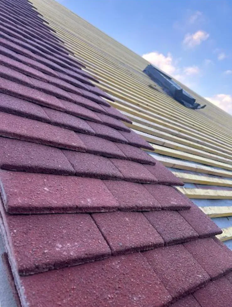 Red plain tiles being laid over new membrane and battens