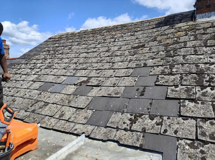 Old slate roof repaired with new slates let into the original coursing