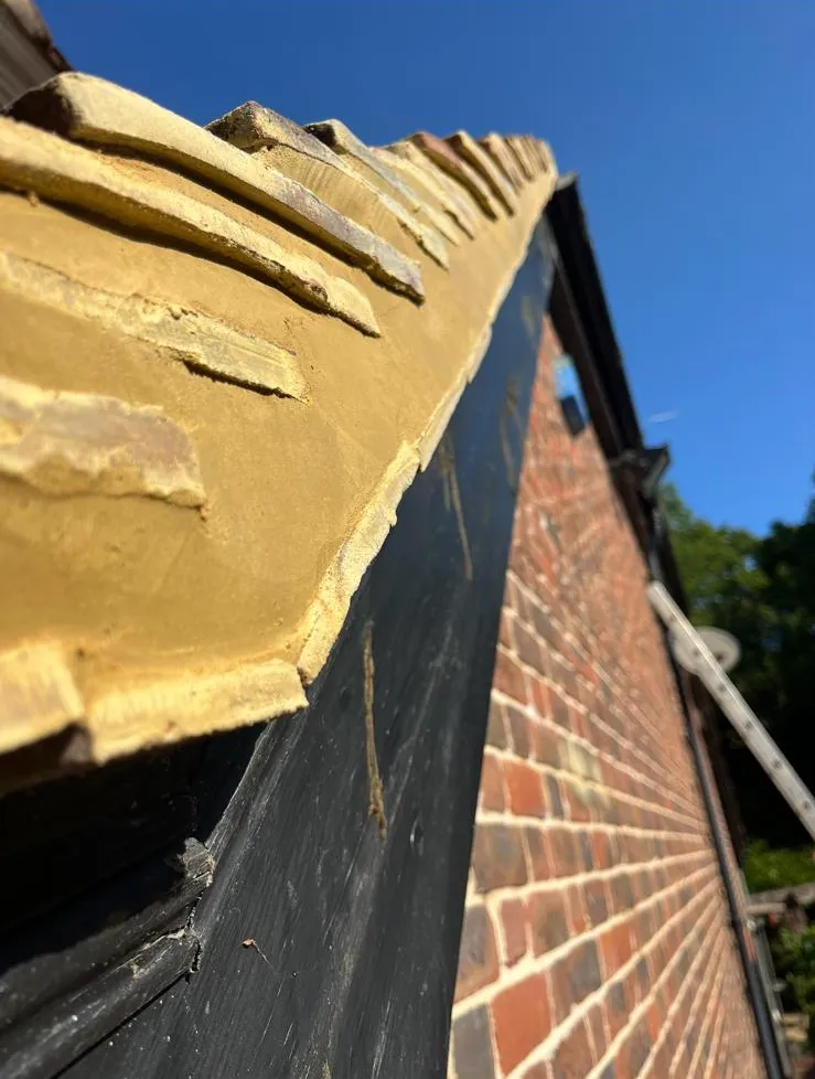 Ridge tiles and verge freshly bedded in mortar against a blue sky