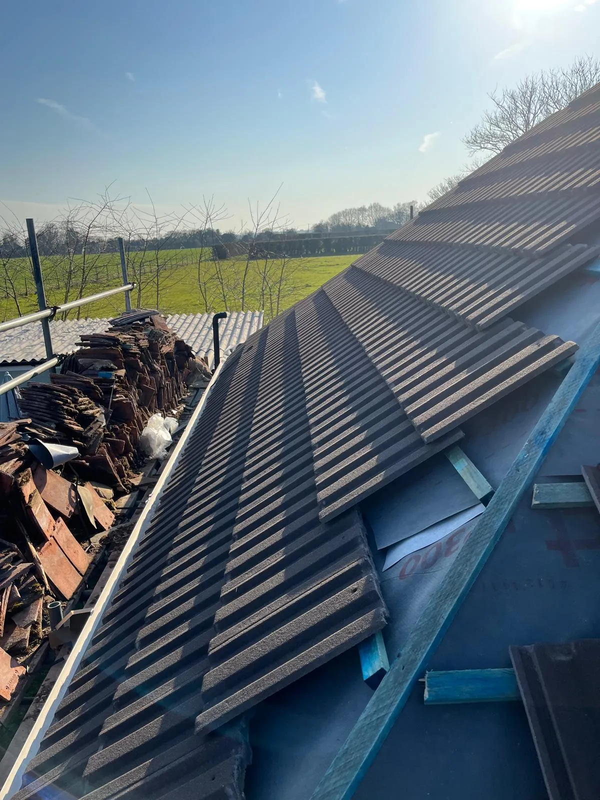Tiles nearing the ridge, old tiles stacked on the scaffold