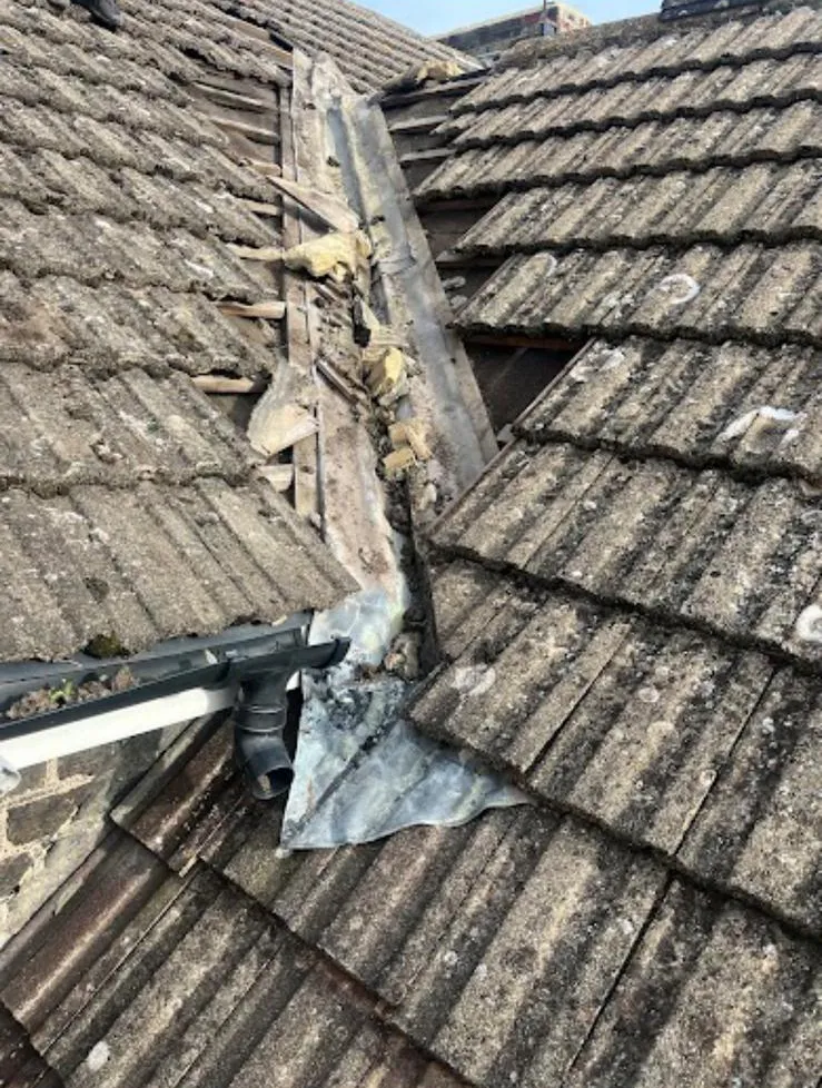 Storm-damaged roof opened up for repair, tiles stripped back to the felt