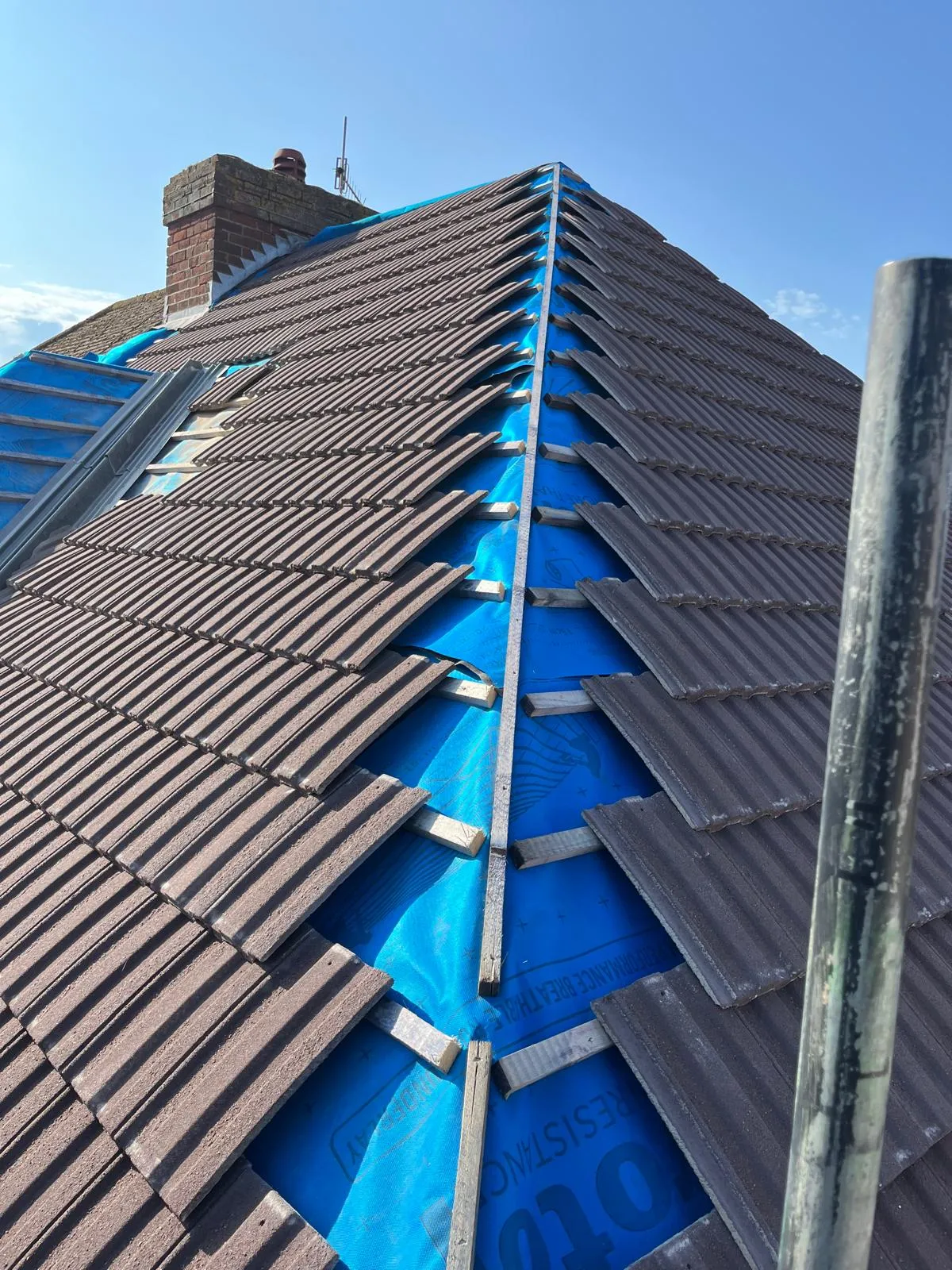 New interlocking tiles being laid over fresh battens on a re-roof